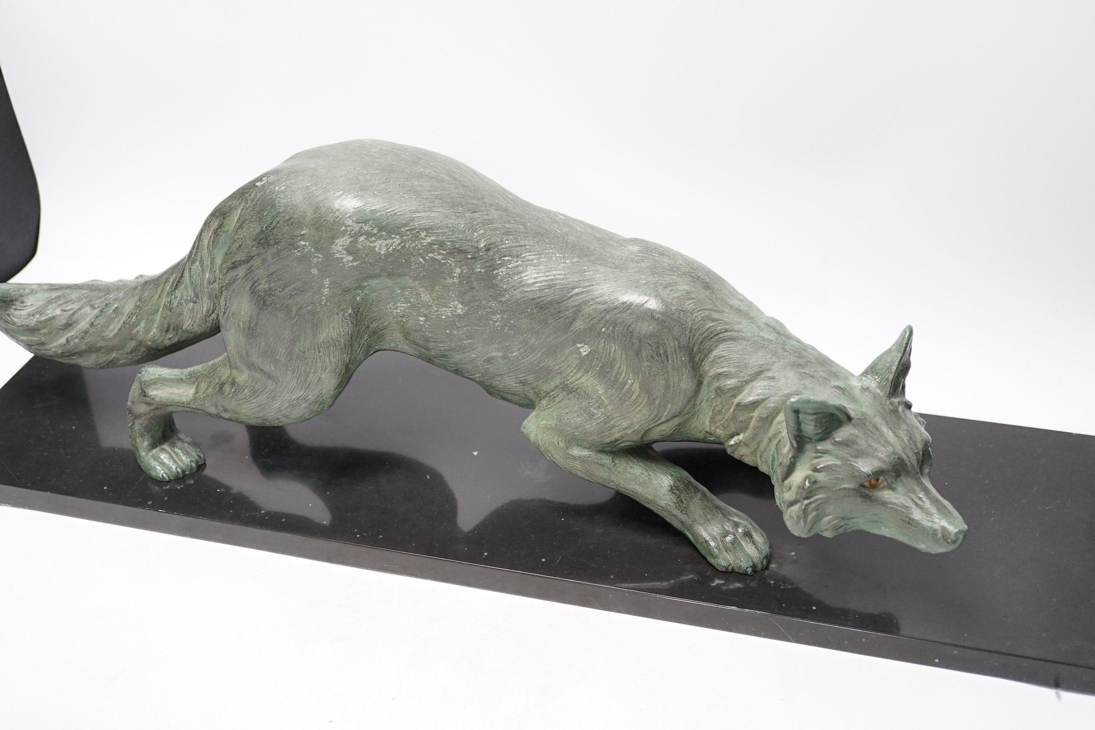 A bronzed metal model of a stalking fox, on black marble plinth, 62cm